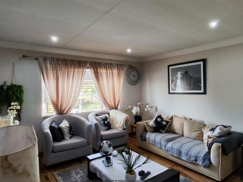 A comfortable living room featuring laminate flooring, recessed downlighting, and decorative cornicing, creating a warm and inviting atmosphere.