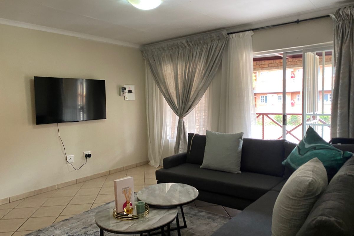 A comfortable living room featuring tiled flooring, a ceiling light fixture, and a sliding glass door providing access to an outdoor area.