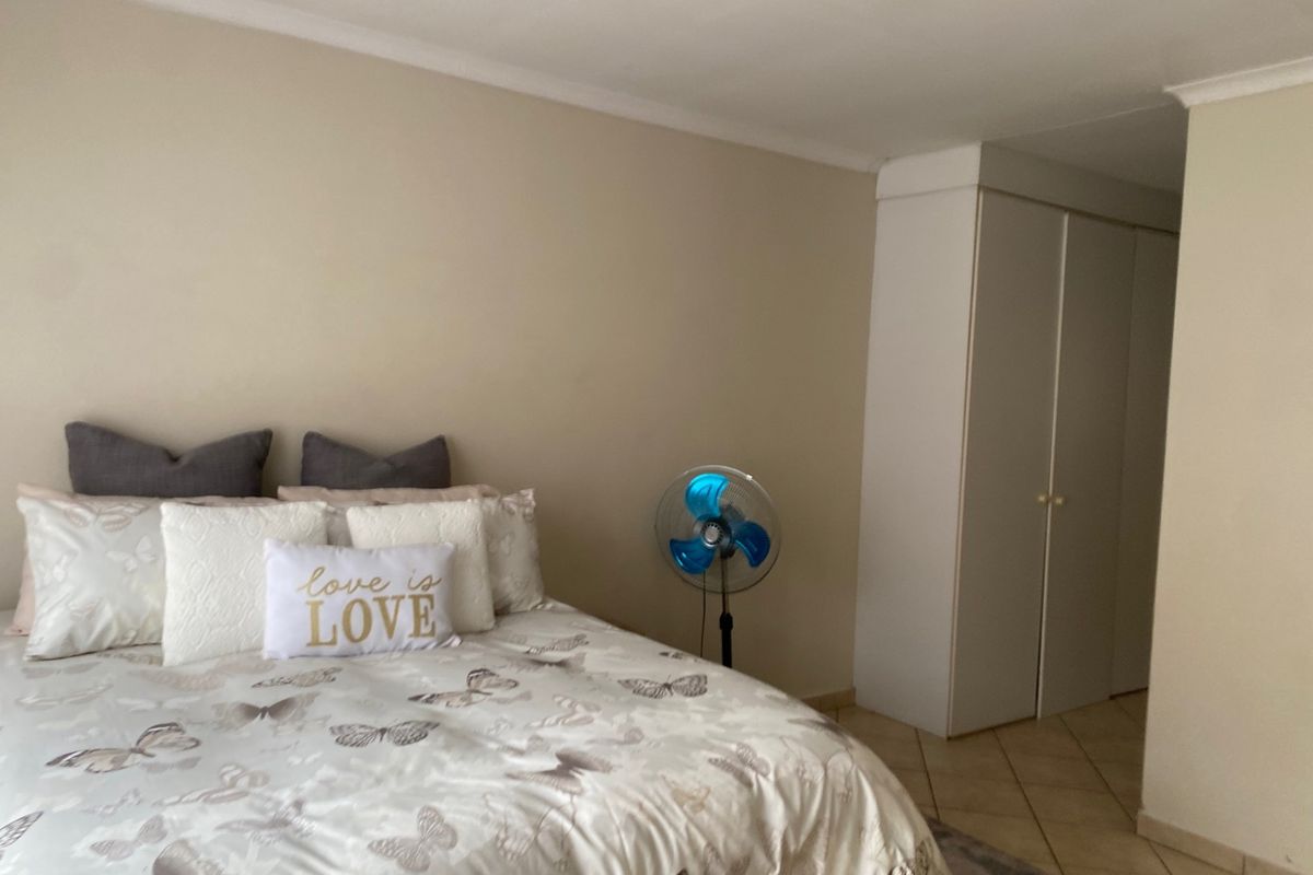 A bedroom featuring neutral walls, tiled flooring, and built-in cupboards, offering a functional and well-maintained living space.