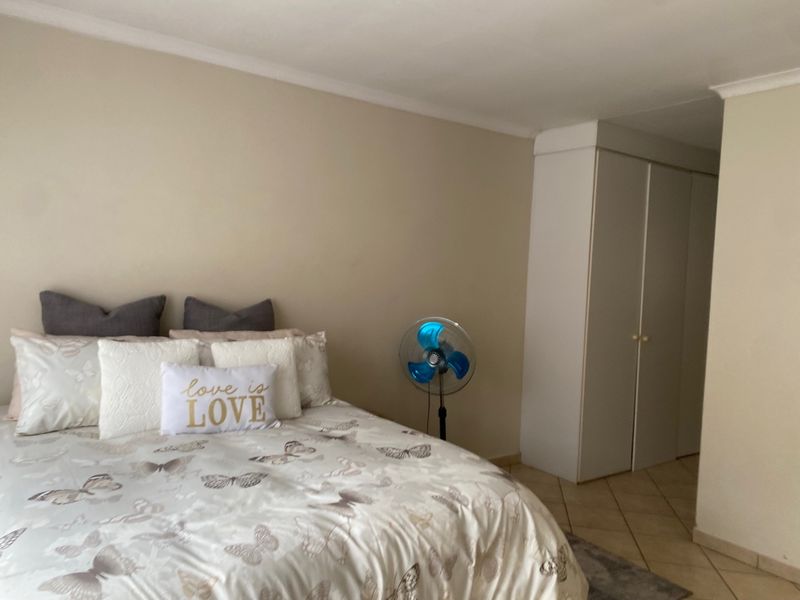 A bedroom featuring neutral walls, tiled flooring, and built-in cupboards, offering a functional and well-maintained living space.