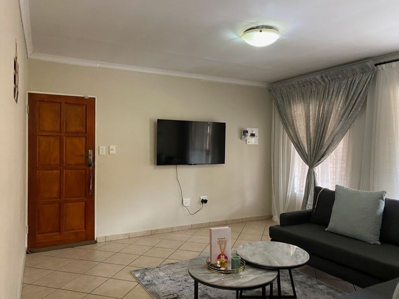 A living room featuring tiled flooring, neutral wall finishes, and a flush mount ceiling light, providing a functional and well-lit space.