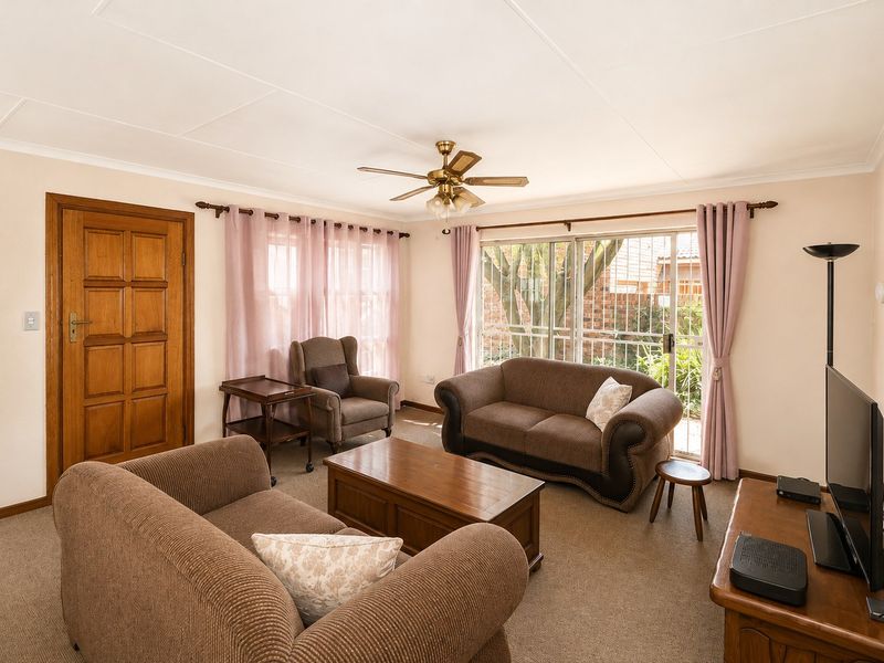 A comfortable living room featuring carpeted flooring, a ceiling fan, and a sliding glass door providing access to the exterior.