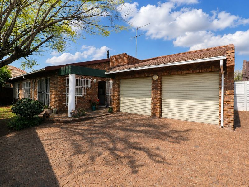 Front elevation of a face brick cluster home featuring a double garage with roll-up doors and a paved driveway.