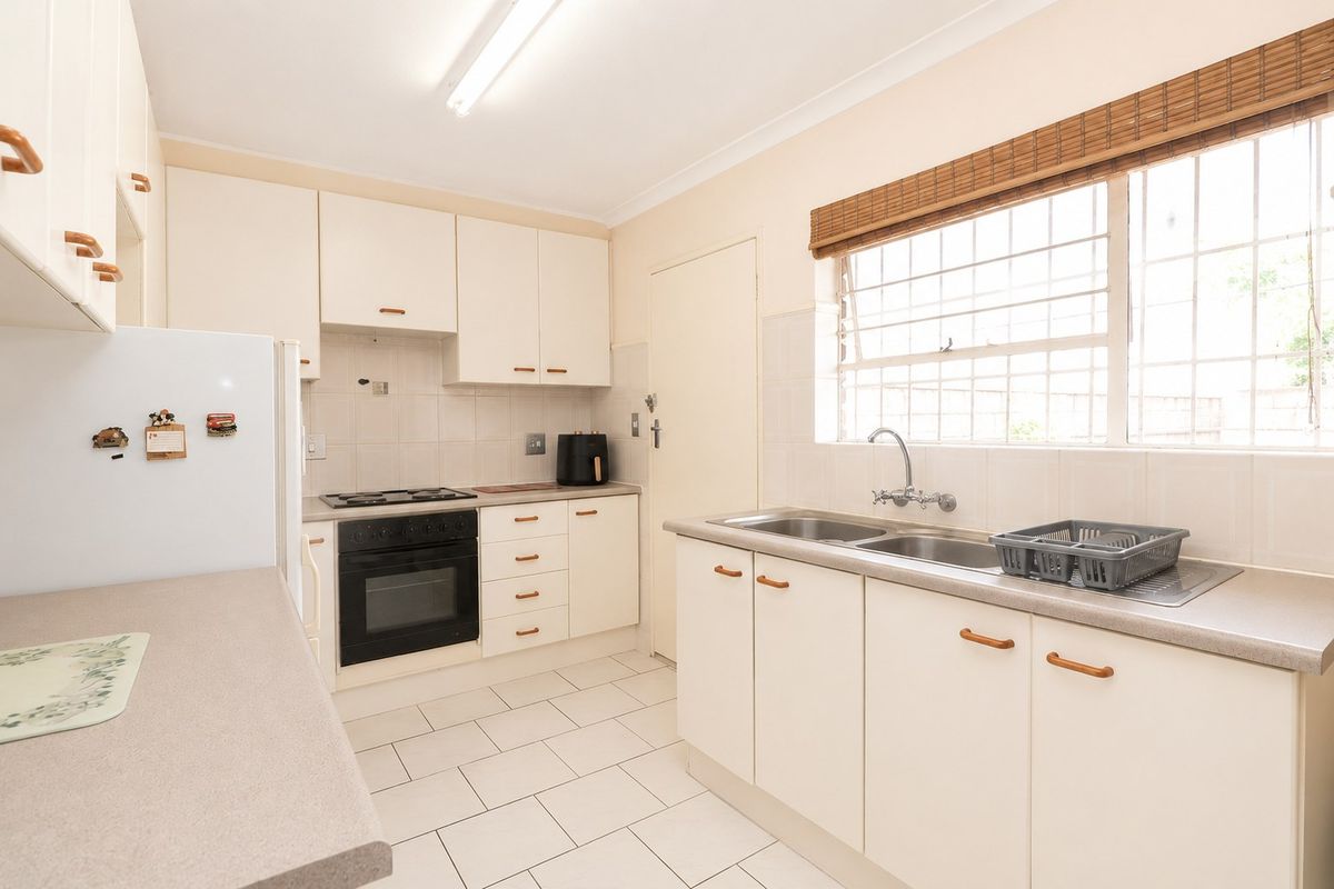 A functional kitchen featuring built-in cabinetry, laminate countertops, a double basin sink, and a built-in oven with an electric hob.