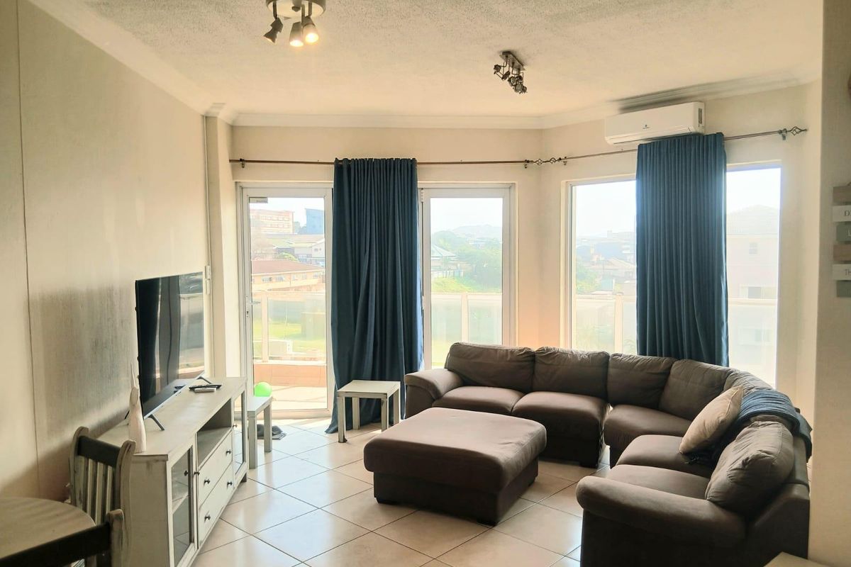 Spacious living room featuring tiled flooring, a ceiling fan, split-system air conditioning, and large sliding glass doors leading to a balcony with views.