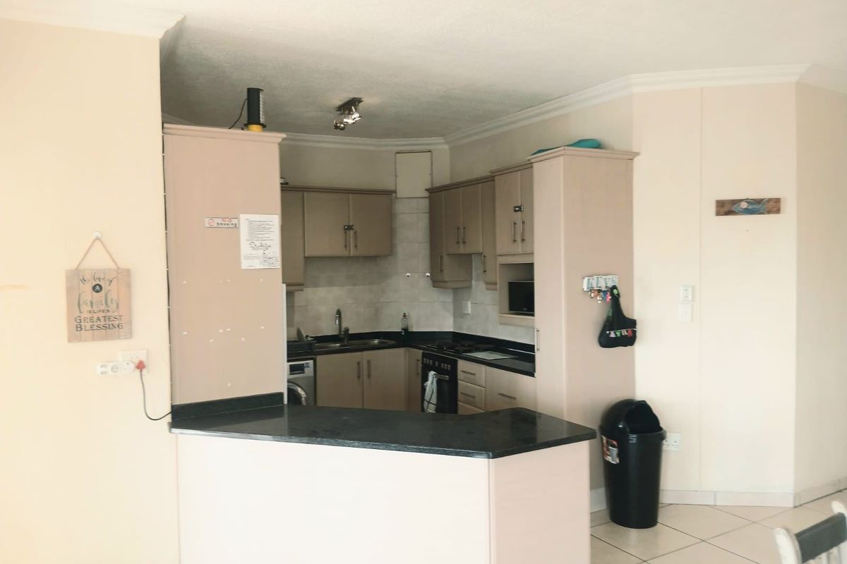A functional kitchen featuring built-in cabinetry, dark laminate countertops, a built-in oven and hob, and tiled flooring in an open-plan layout.