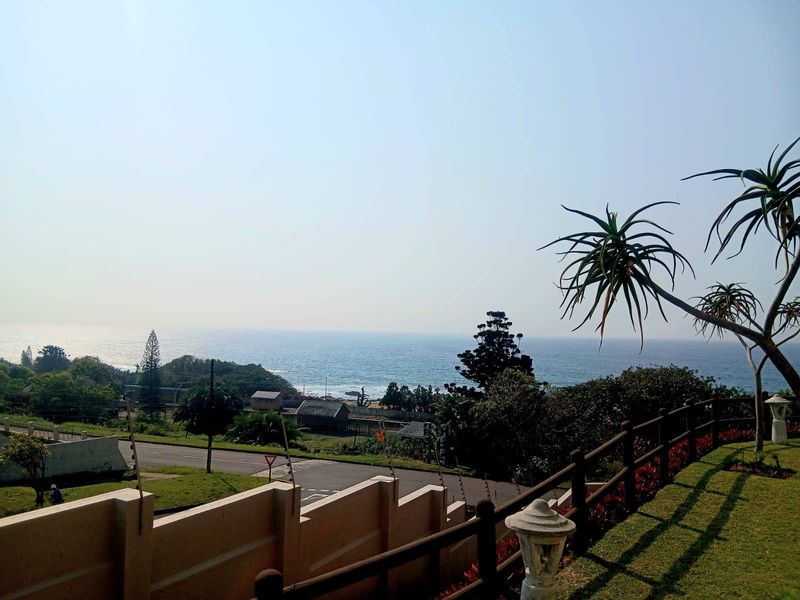 Elevated coastal view overlooking the ocean, featuring a landscaped garden area with perimeter wall, electric fencing, and timber railing.
