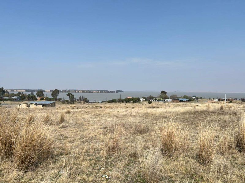 A wide-angle view of the vacant residential land overlooking a large water body and surrounding landscape.
