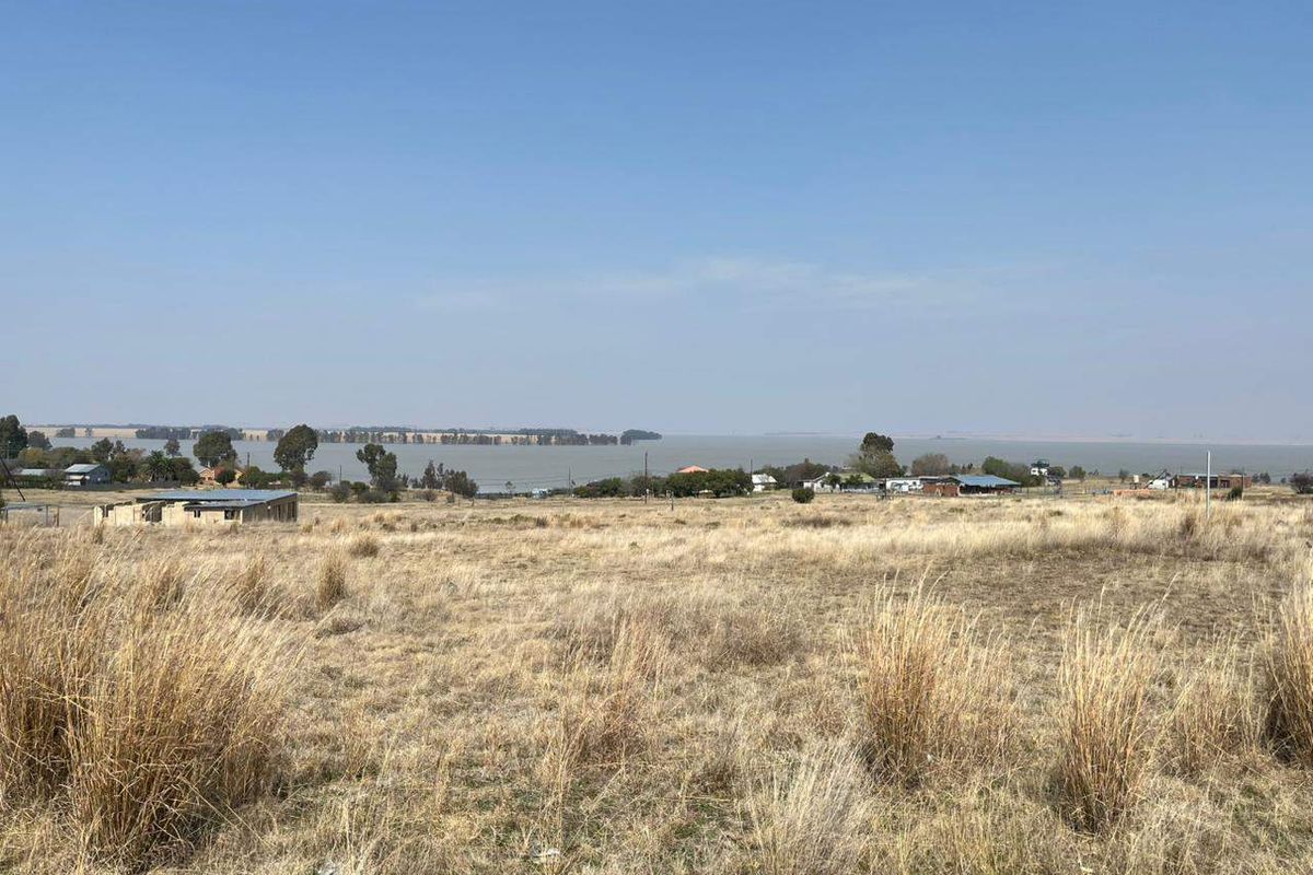 A wide-angle view of the vacant residential land overlooking a large water body and surrounding landscape.