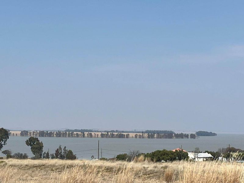 A scenic view overlooking a large water body and distant treeline, showcasing the natural landscape surrounding the vacant residential land.