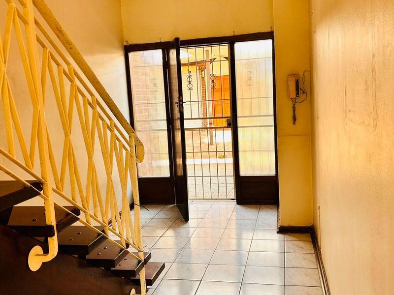 Entrance foyer featuring tiled flooring, a staircase with a metal balustrade, and a security gate leading to the exterior.