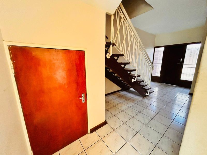 Entrance foyer featuring tiled flooring, a wooden staircase with decorative wrought iron balustrade, and a solid wood door.