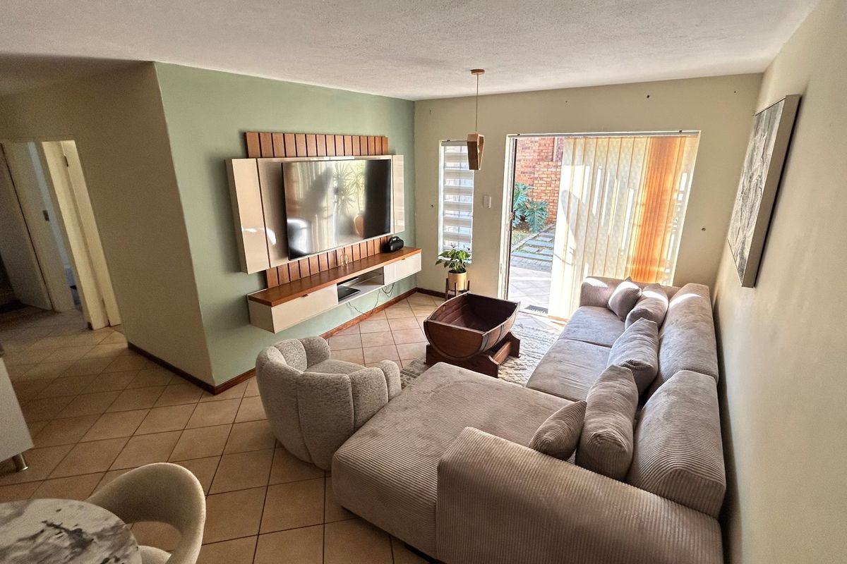 A comfortable living room featuring a built-in media console, ceramic tile flooring, and direct access to an outdoor patio area through sliding glass doors.
