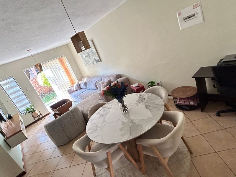 Open-plan living and dining area featuring tiled flooring, pendant lighting, and a sliding glass door providing access to the exterior.