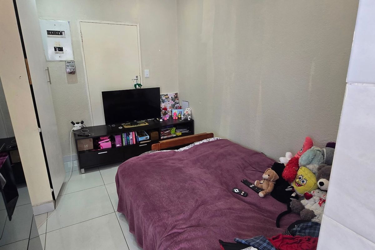 A compact bedroom featuring tiled flooring and a wall-mounted electrical distribution board.