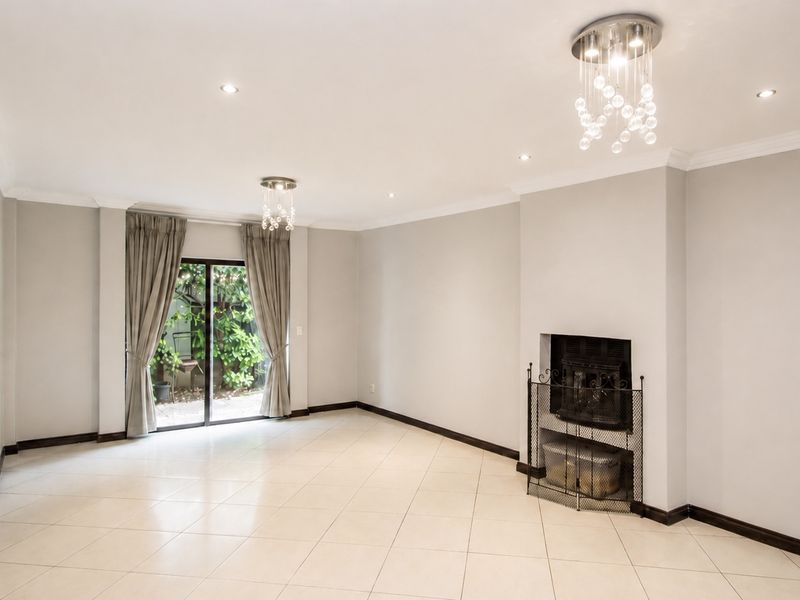 Spacious living room featuring neutral tiled floors, a built-in fireplace, and sliding glass doors that open to the garden area.