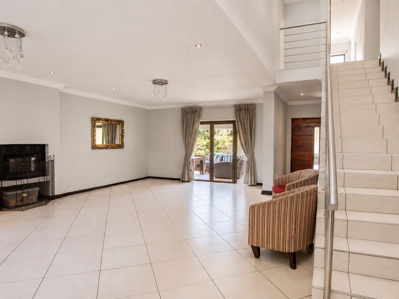 Spacious open-plan living area featuring tiled floors, a built-in fireplace, and a modern staircase leading to the upper level with access to the patio.