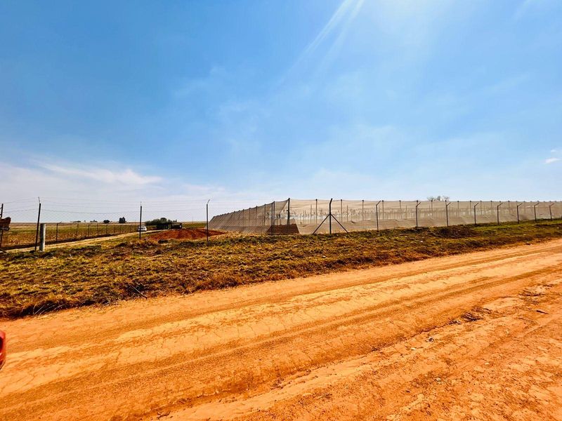 A view of the farm property featuring extensive perimeter fencing and agricultural netting structures set against a rural landscape.