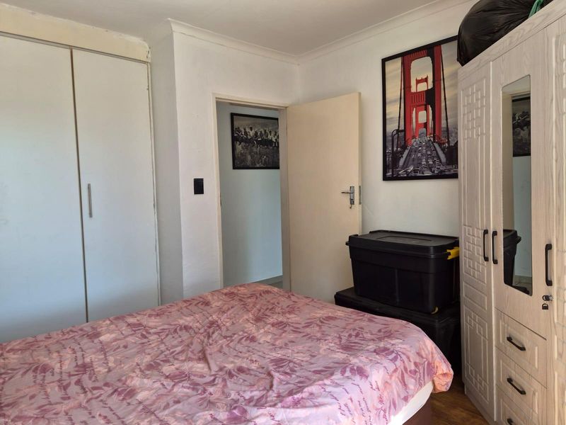 A functional bedroom featuring built-in cupboards and coved ceiling detailing, providing a practical living space with standard finishes.