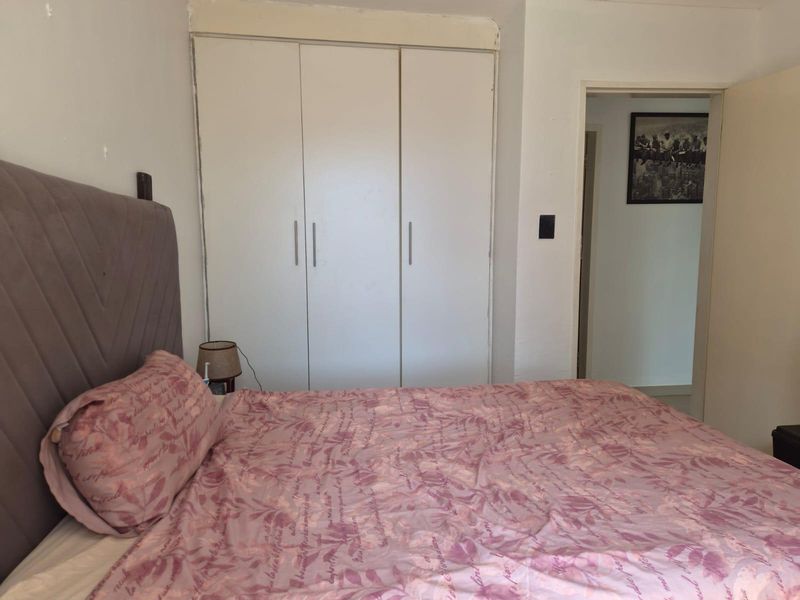 A bedroom featuring a built-in wardrobe with white doors and access to an adjoining hallway.