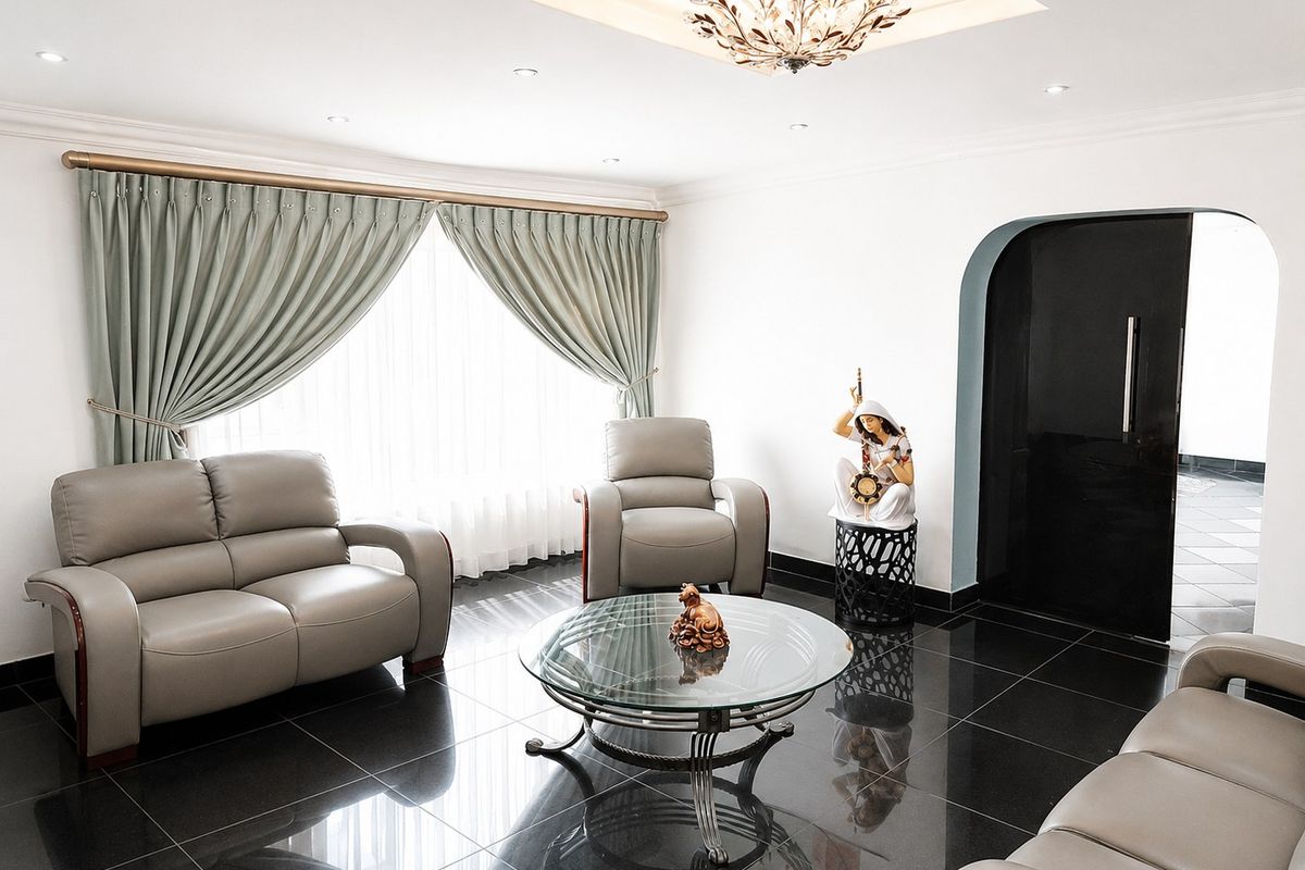 A well-maintained living room featuring polished tile flooring, an arched doorway, and recessed ceiling lighting with a decorative central fixture.