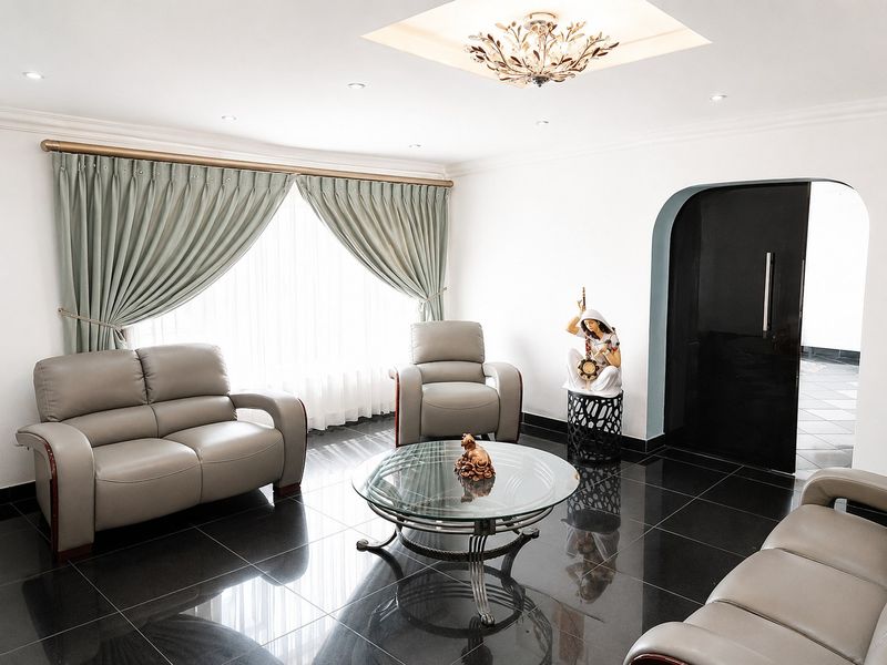 A well-maintained living room featuring polished tile flooring, an arched doorway, and recessed ceiling lighting with a decorative central fixture.