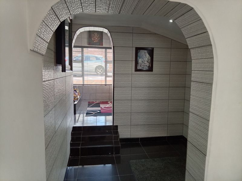 An entrance area featuring an arched doorway, modern tiled wall finishes, and a stepped transition leading to an adjacent space.
