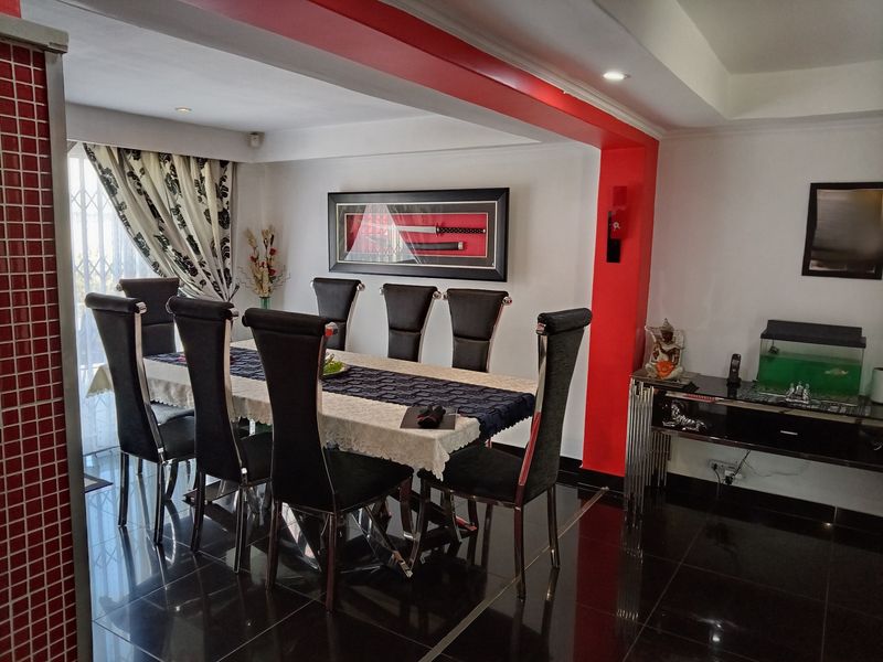 A dining room featuring high-gloss tiled flooring, recessed ceiling lighting, and a sliding glass door with security gate access to the exterior.