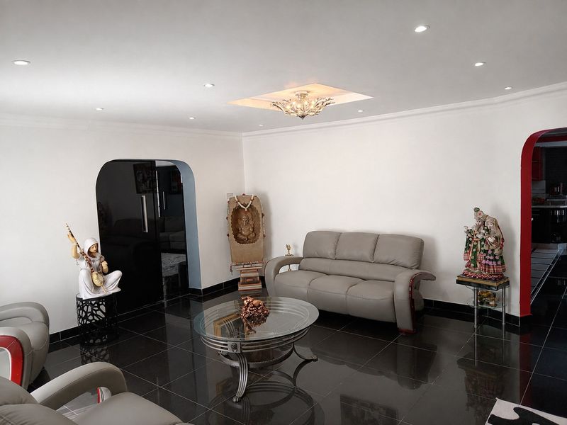 A well-maintained living room featuring glossy floor tiles, recessed downlighting, and an elegant arched doorway leading to adjacent spaces.
