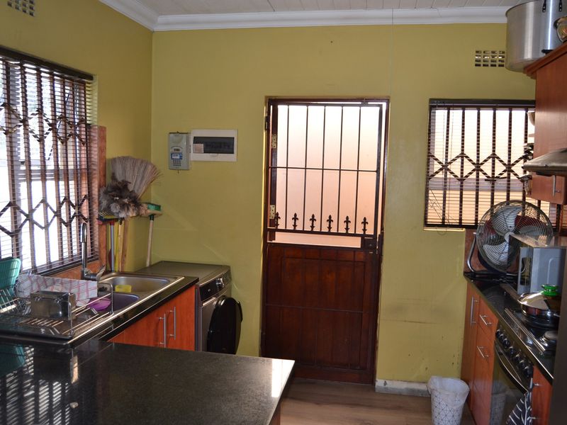 Functional kitchen featuring granite countertops, built-in cabinetry, and a secure exterior door with security gate.