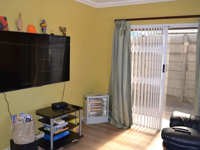 A living room featuring laminate flooring, a coved ceiling, and a sliding glass door with an integrated security gate leading to the exterior.