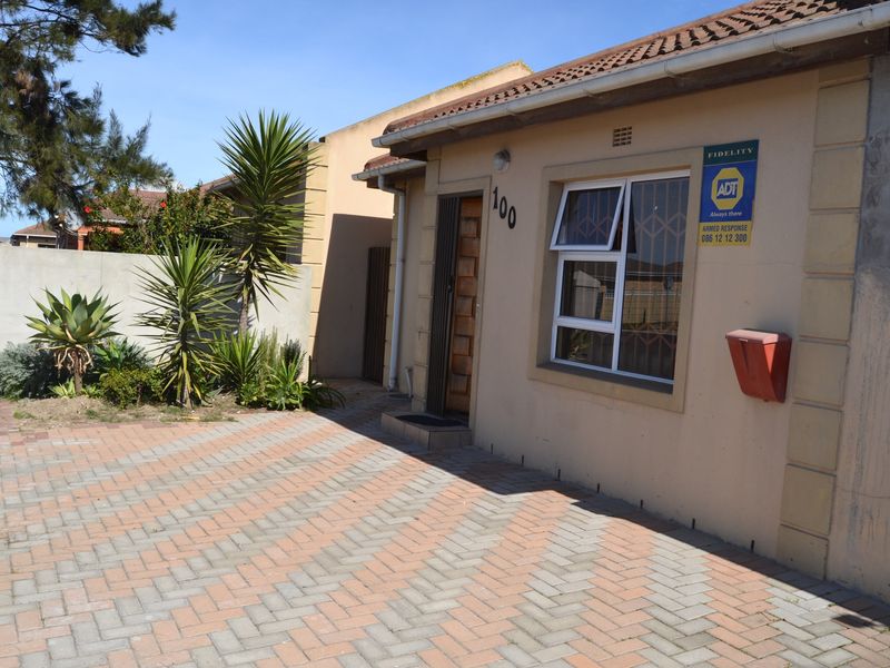 Front elevation of a residential house featuring a paved driveway, security gate, and perimeter walling.