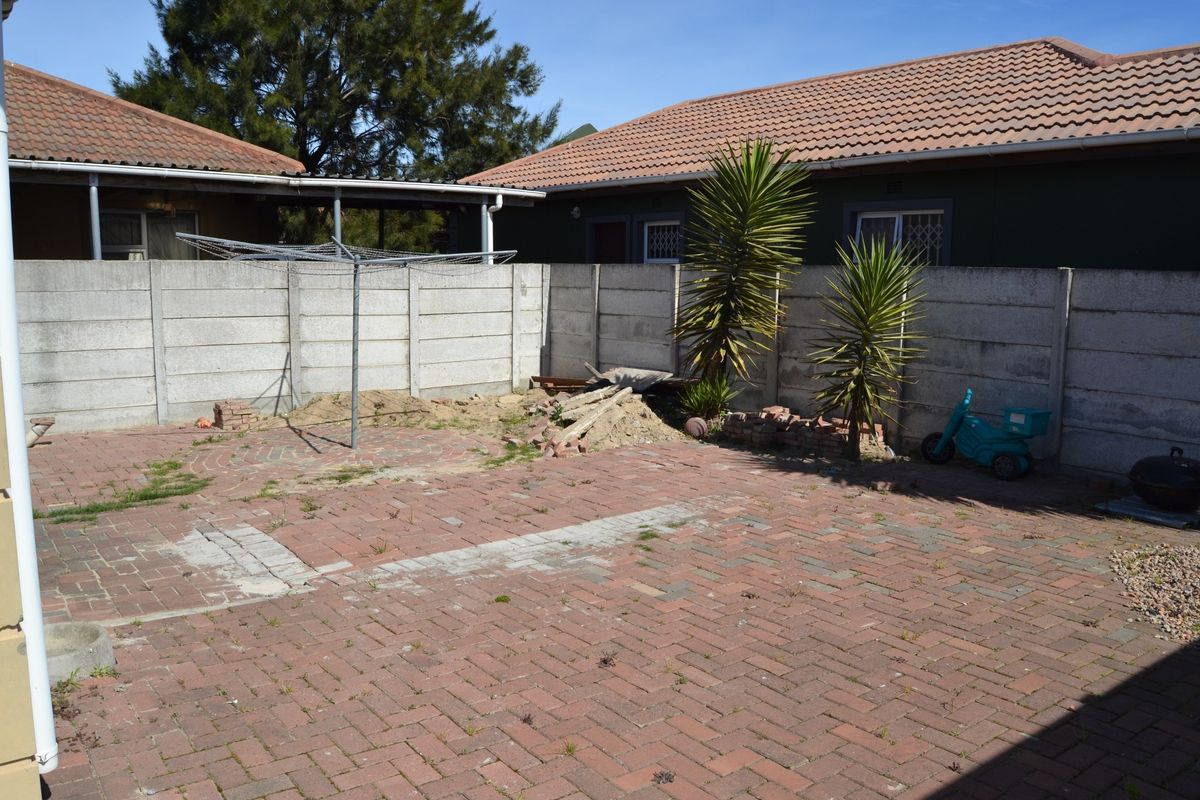 A rear courtyard area featuring brick paving and perimeter precast concrete walling, requiring some maintenance and landscaping to improve the outdoor space.