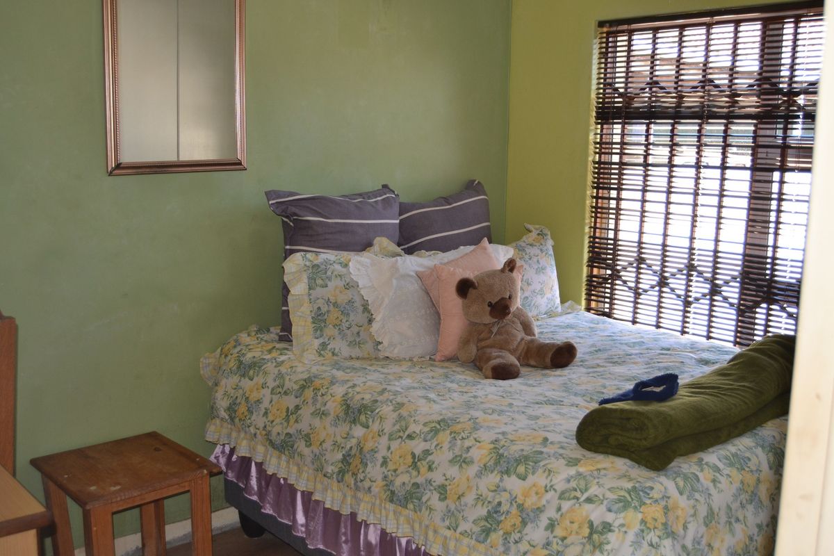 A bedroom featuring green painted walls, a window with venetian blinds, and an integrated security gate.