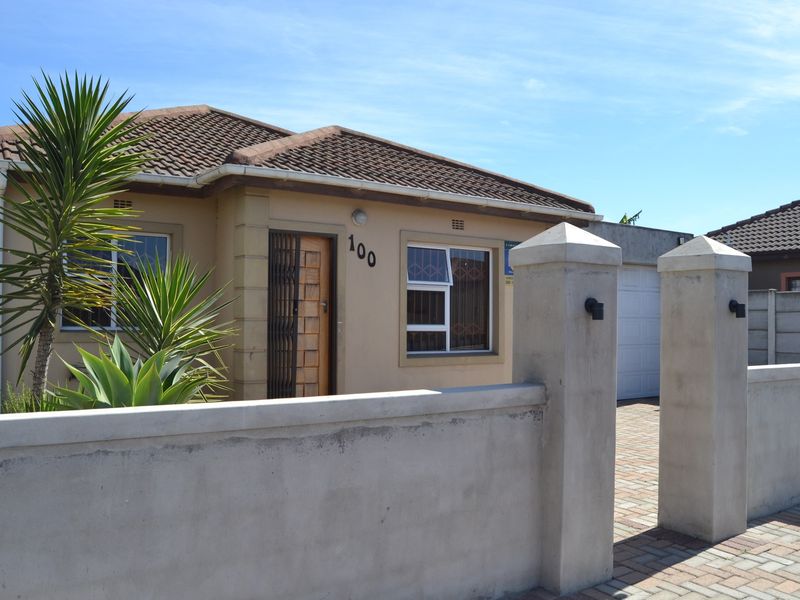 Front view of a single-story house featuring a tiled roof, paved driveway, and a secure boundary wall with integrated lighting.