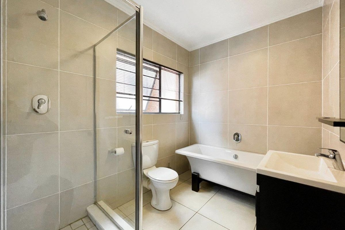 Modern bathroom featuring a walk-in shower with glass enclosure, a freestanding bathtub, wall-mounted vanity basin, and neutral floor-to-ceiling tiling.