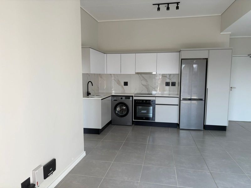 Modern kitchen featuring white cabinetry, marble-look splashback, integrated oven, extractor fan, and sleek tiled flooring in an open-plan layout.