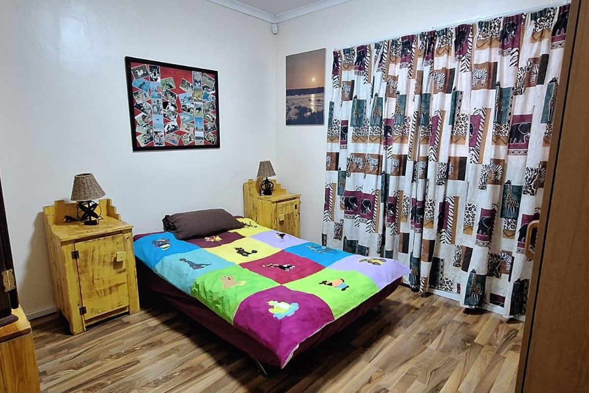 A bedroom featuring laminate flooring and built-in cupboards, offering a functional space with neutral wall finishes.