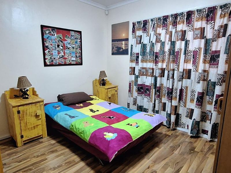 A bedroom featuring laminate flooring and built-in cupboards, offering a functional space with neutral wall finishes.