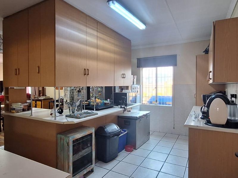 Functional kitchen featuring laminate cabinetry, tiled flooring, and ample counter space, offering a practical layout with potential for modern updates.