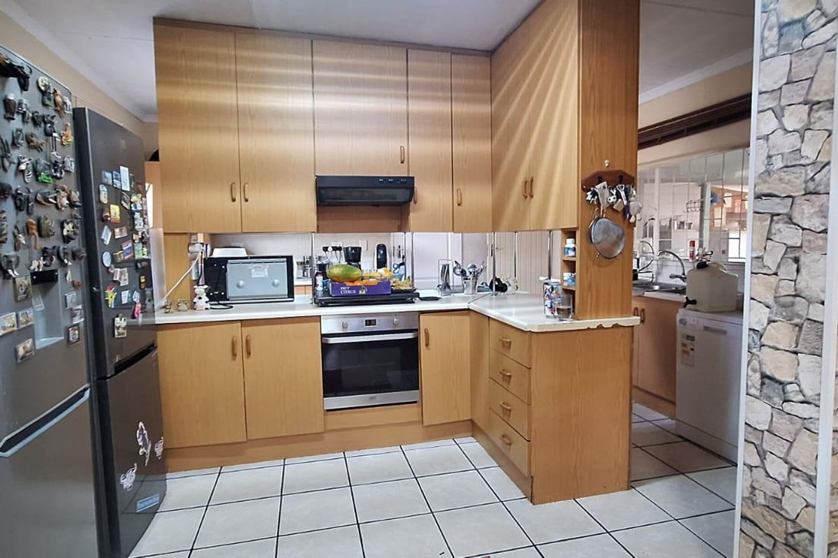 Functional kitchen featuring laminate cabinetry, built-in oven, extractor fan, and ceramic tile flooring, with an adjacent scullery area visible.