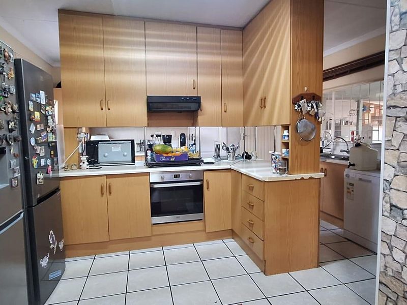 Functional kitchen featuring laminate cabinetry, built-in oven, extractor fan, and ceramic tile flooring, with an adjacent scullery area visible.