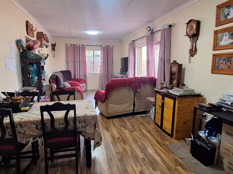 An open-plan living and dining area featuring laminate flooring and natural light, providing a functional space for daily living.