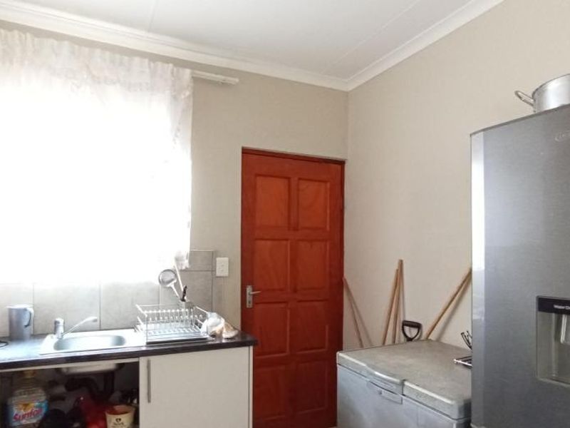 A functional scullery area featuring built-in cabinetry, a stainless steel sink, and tiled splashback, providing practical utility space for the home.