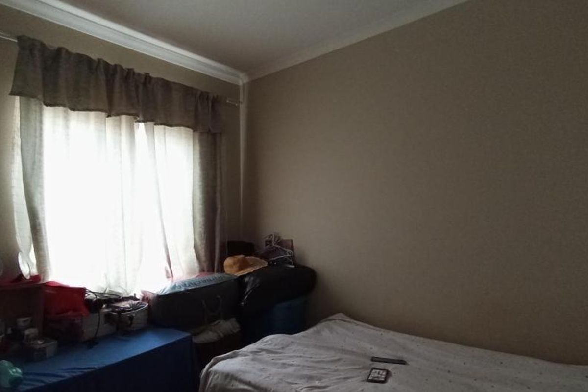 A standard bedroom featuring neutral wall paint and a window with fitted curtain rails.