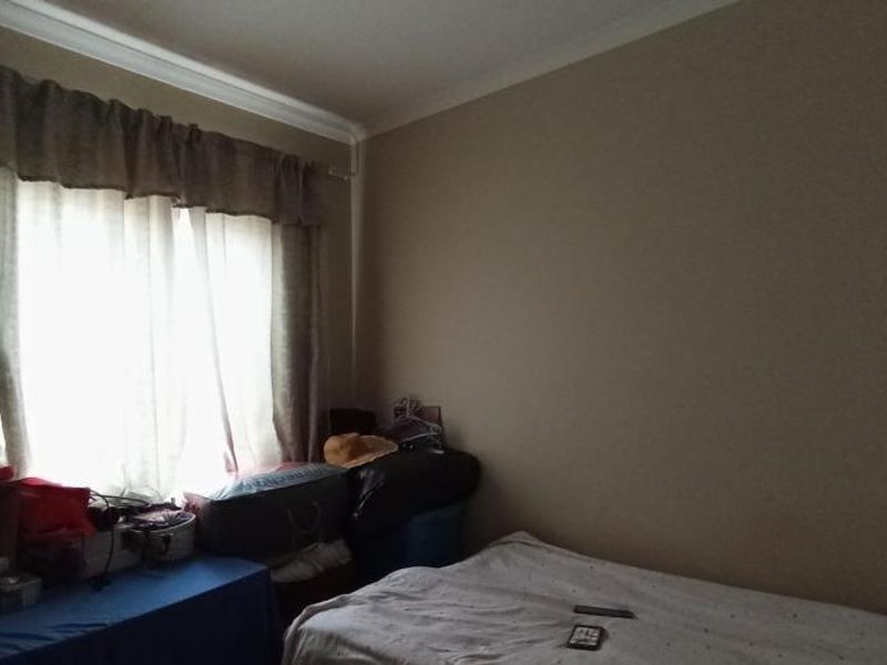 A standard bedroom featuring neutral wall paint and a window with fitted curtain rails.