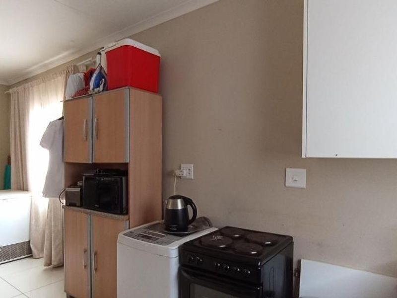 A functional kitchen area featuring built-in cabinetry, an electric stove, and tiled flooring, offering a practical layout for daily meal preparation.
