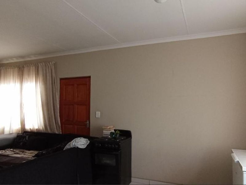 A living room area featuring neutral wall tones, coved ceilings, and a timber door, providing a functional and versatile living space.