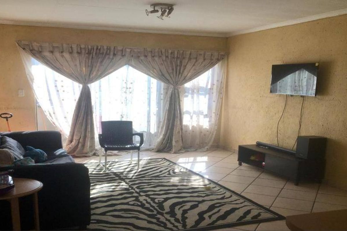 A living room featuring tiled flooring and a large sliding glass door providing natural light.