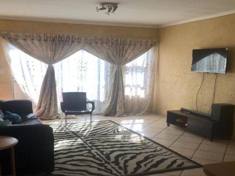 A living room featuring tiled flooring and a large sliding glass door providing natural light.